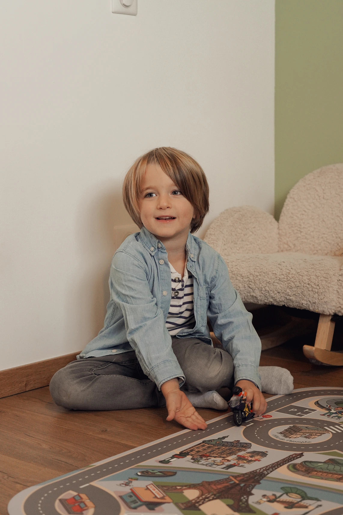 Un petit garçon joue avec ses voitures miniatures sur un tapis de jeu Paris